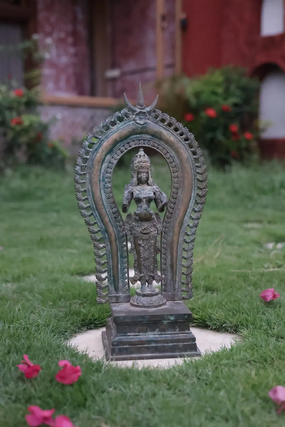 A bronze standing deity in an arched frame